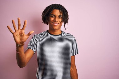 Zencili pembe arka planda duran lacivert çizgili t-shirt ayakta giyen dreadlocks ile Afro adam gösteren ve parmak sayısı beş ile işaret kadar güven ve mutlu gülümseyen.
