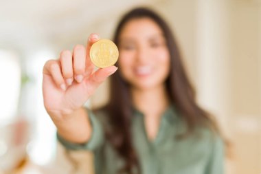 Elektronik ödeme olarak Bitcoin cryptocurrency tutan gülümseyen genç kadın