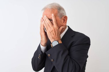 Üst düzey gri saçlı işadamı takım elbise giyen izole beyaz arka plan üzerinde ayakta üzgün ifade ile elleri ile yüz kapsayan ağlarken. Depresyon kavramı.
