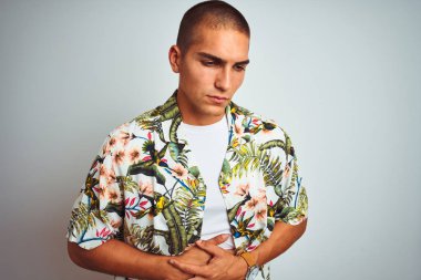 Tatillerde genç yakışıklı adam midenin el ile beyaz arka plan üzerinde Hawaii gömlek giyiyor çünkü hazımsızlık, ağrılı hastalık duygusunu. Ağrı kavramı.