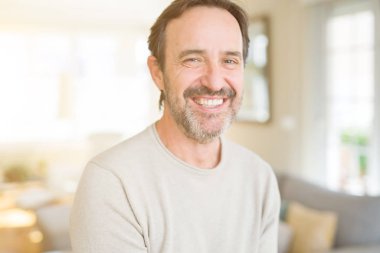 Evde kameraya bakarak gülümseyen yakışıklı orta yaş erkek