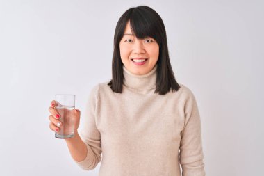 Genç güzel Çinli kadın ayakta mutlu bir yüz ile izole beyaz arka plan üzerinde su tutarak cam ve diş gösteren emin bir gülümseme ile gülümseyen