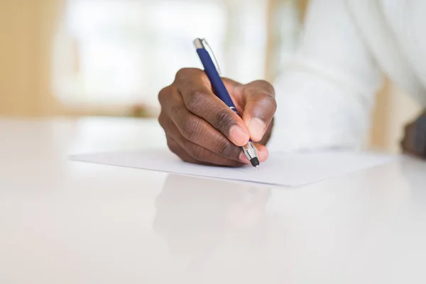 Close-up van de Afrikaanse man het schrijven van een briefje op een papier — Stockfoto