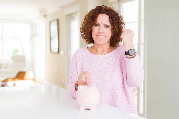 Mulher Sênior Economizando Dinheiro Colocando Uma Moeda Dentro Mealheiro Irritado — Fotografia de Stock
