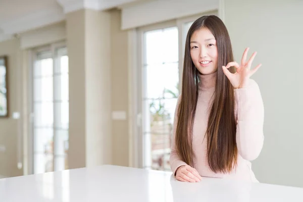 Hermosa Mujer Asiática Con Suéter Casual Mesa Blanca Sonriendo Positiva —  Fotos de Stock