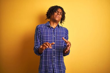 Dreadlocks ile Afro adam izole sarı arka plan mide bulandırılmış ifade üzerinde ayakta giyerek, nefret ve korkuyla nefreti yüz yapıyor çünkü kaçınma reaksiyon. Ellerle kaldırdı. Rahatsız edici kavramı.