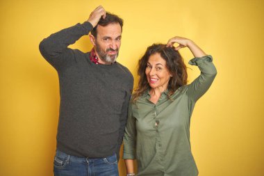 İzole sarı arka plan üzerinde güzel orta yaş çift karıştırır ve soru hakkında merak ediyorum. Şüphe ile belirsiz, baş el ile düşünme. Pensive kavramı.