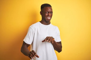 Genç Afrikalı Amerikalı adam beyaz t-shirt üzerinde ayakta izole sarı arka plan mide bulandırdı ifade, hoşnutlu ve korkuyla acı yüz yapıyor çünkü kaçınma reaksiyon. Ellerle kaldırdı. Rahatsız edici kavramı.