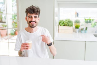 Genç adam sabah bir kağıt fincan bir kahve içme sürpriz yüz kendisine parmak işaret ile