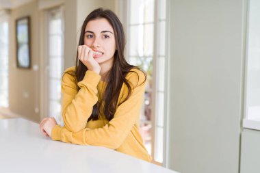 Sarı kazak giyen güzel genç kadın vurgulandı ve ağız ısırma tırnakları ile gergin bakıyor. Anksiyete sorunu.