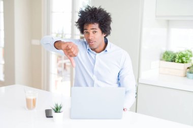 Afrika kökenli Amerikalı iş adamı dizüstü kullanarak kızgın yüzü, eksi işareti aşağı antipati başparmak ile gösterilen, ret kavramı ile çalışma