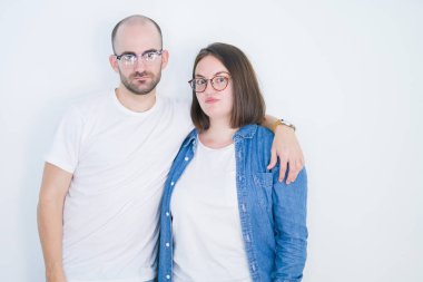 Genç çift birlikte beyaz izole arka plan üzerinde sağlam bir ifade ile akıllı yüz düşünme ciddi üzerinde gözlük giyiyor
