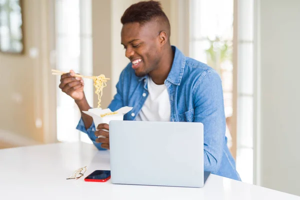 Handsome young african business man eating delivery asian food a