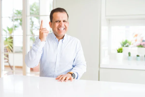 Hombre Mediana Edad Sentado Casa Señalando Con Dedo Hacia Arriba — Foto de Stock