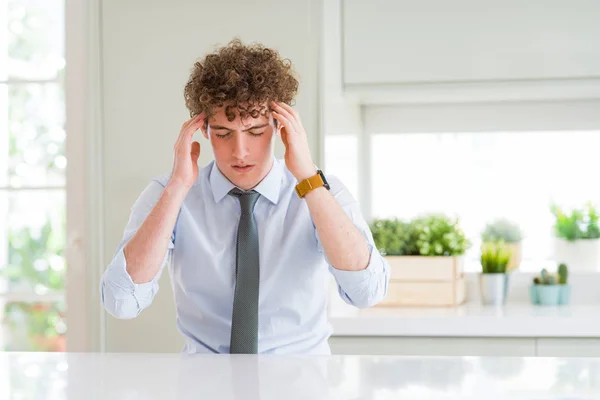 Young business man wearing a tie with hand on head for pain in head because stress. Suffering migraine.