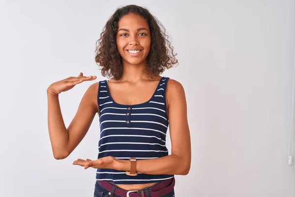 孤立した白い背景の上に立つストライプのTシャツを着た若いブラジル人女性は 大きくて大きなサイズの看板を示す手で身振り手を振り シンボルを測定します カメラを見て微笑む 測定コンセプト — ストック写真