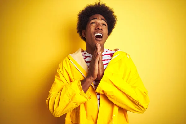 노란색 비옷을 아프리카 미국인 남자는 감정적이고 얼굴에 표정과 손으로 구걸하고기도합니다 — 스톡 사진