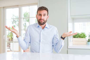 Yakışıklı iş adam clueless ve şaşkın bir ifadeyle kollar ve eller kaldırdı. Şüphe kavramı.
