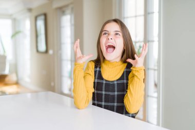 Güzel genç kız çocuk masaya oturan deli ve deli bağırarak ve saldırgan ifade ve silah ile bağırdı kaldırdı. Hayal kırıklığı kavramı.