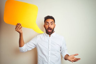 Genç Arap Hint İspanyol adam tutma konuşma kabarcık üzerinde izole beyaz arka plan çok mutlu ve heyecanlı, kazanan ifade zafer kutlama ile çığlık büyük gülümseme ve yükseltilmiş eller