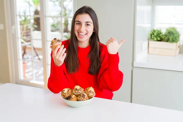 チョコレートチップを食べる美しい若い女性は 笑顔で笑顔で横に親指で指差し 見せる — ストック写真