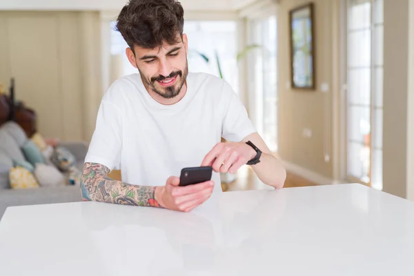 Jovem com tatuagem vestindo camiseta branca casual usando smartph — Fotografia de Stock