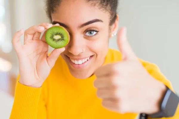 年轻的非洲美国女孩吃绿色奇异果快乐与大微笑做Ok标志 拇指用手指 优秀的标志 — 图库照片