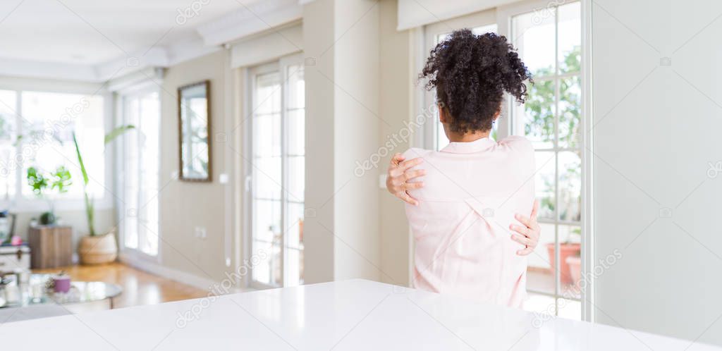Wide angle of beautiful african american woman with afro hair Hugging oneself happy and positive from backwards. Self love and self care
