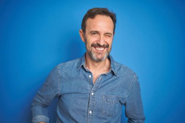 Seksi ifade, neşeli ve mutlu yüz ile kamera bakarak izole mavi arka plan üzerinde gri saçlı yakışıklı orta yaş kıdemli adam.