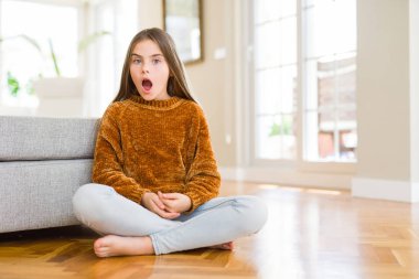 Güzel genç kız çocuk evde korkuyor ve şok sürpriz ifade, korku ve heyecan yüz ile katta oturan.