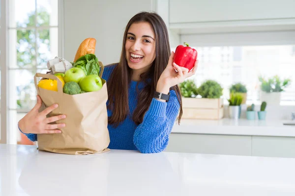 Молода красива жінка посміхається тримає паперовий мішок повний продуктовий — стокове фото