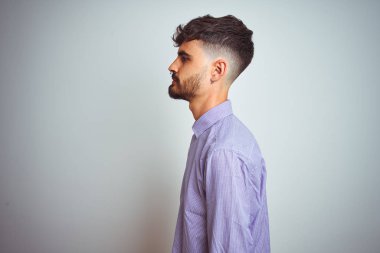 Yan bakan izole beyaz arka plan üzerinde duran mor gömlek giyen dövme giyen genç adam, kendine güvenen gülümseme ile doğal yüzü ile profil poz dinlenmek.