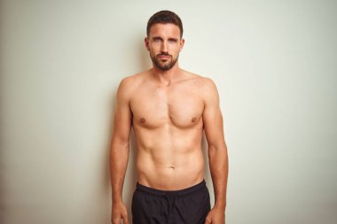 İzole arka plan üzerinde genç yakışıklı gömleksiz adam şüpheci ve sinir, sorun nedeniyle üzgün çatık. Negatif kişi.