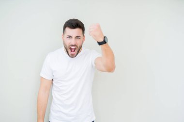Öfkeli ve sinirli sinirli ve öfke ile bağırarak süre öfkeli yumruk yükselterek izole arka plan üzerinde rahat beyaz t-shirt giyen genç yakışıklı adam. Öfke ve agresif kavramı.