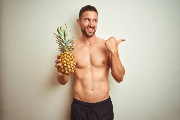 Handsome Shirtless Man Wearing Swimwear Holding Pineapple Isolated Background Pointing — Stock Photo, Image