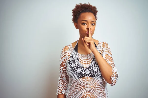 Young african american woman with afro hair wearing a bikini over white isolated background asking to be quiet with finger on lips. Silence and secret concept.