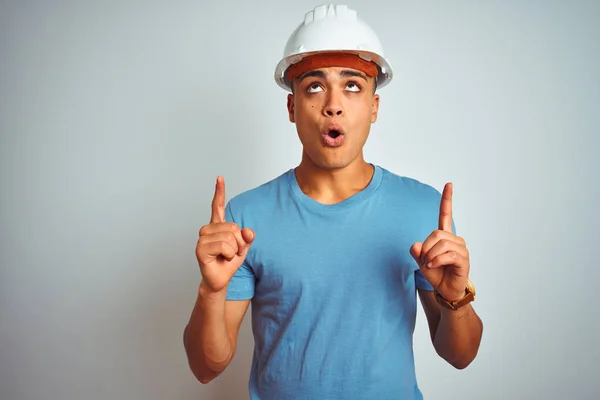 年轻的巴西工程师男子戴着安全帽站在孤立的白色背景惊讶和惊讶抬头 手指和抬起手臂 — 图库照片