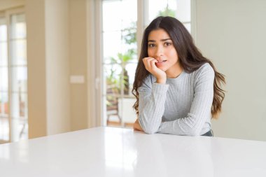 Genç güzel kadın evde stresli ve gergin elle çivi ısırma ağzına bakıyor. Anksiyete sorunu.