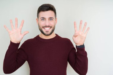 Genç yakışıklı adam izole arka plan üzerinde bir kazak giyen gösteren ve emin ve mutlu gülümserken parmakları ile dokuz numara işaret.