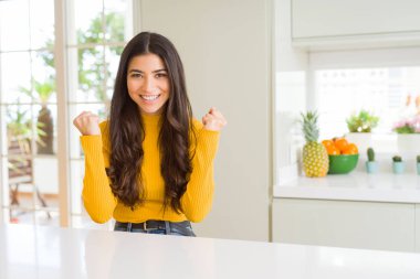 Beyaz masada evde genç güzel kadın şaşırttı ve silah yükseltilmiş ve açık gözleri ile başarı için hayran kutluyor. Kazanan kavramı.