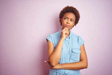 Genç güzel afro-amerikan kadın üzerinde izole pembe arka plan üzerinde çene üzerinde soru, dalgın ifade düşünme. Düşünceli bir yüzle gülümsüyor. Şüphe kavramı.