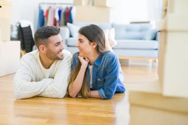 Junges schönes Paar, lächelnd auf dem Boden des neuen Hauses liegend — Stockfoto