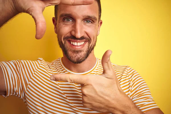 特写年轻帅哥穿着休闲T恤 在黄色孤立的背景微笑 用手和手指与快乐的脸框 创意与摄影理念 — 图库照片