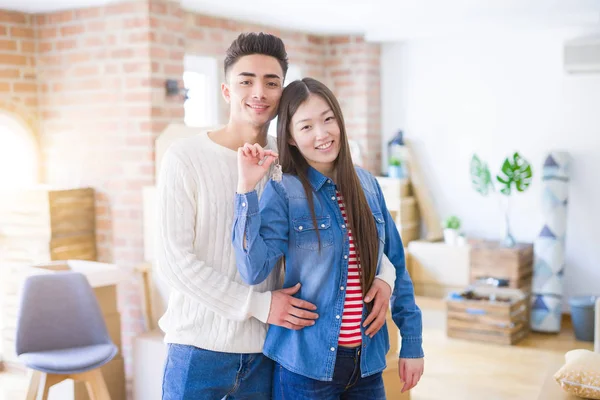 Молода азіатська пара тримає ключі від нового будинку, посміхаючись щасливий і — стокове фото