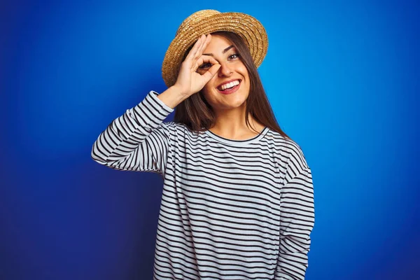 줄무늬 티셔츠와 모자를 파란색 행복한 얼굴로 손가락을 눈으로 제스처를하고있는 아름다운 — 스톡 사진