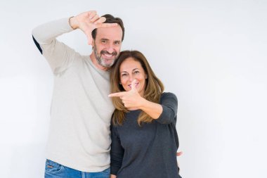 Güzel orta yaş çift elle yapma çerçeve ve parmakları ile mutlu yüz gülümseyen izole arka plan üzerinde aşık. Yaratıcılık ve Fotoğrafçılık kavramı.