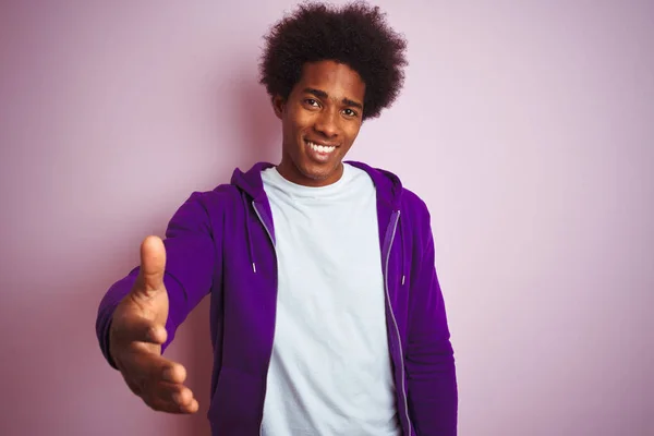 年轻的非洲裔美国男子穿着紫色运动衫站在孤立的粉红色背景微笑友好提供握手作为问候和欢迎 成功的业务 — 图库照片
