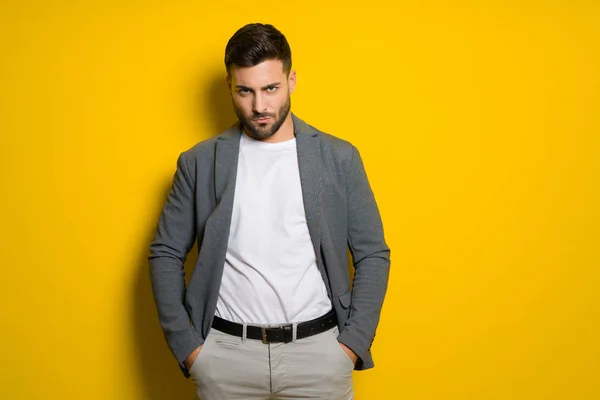 Jovem homem bonito possuindo e modelagem sobre bac isolado amarelo — Fotografia de Stock