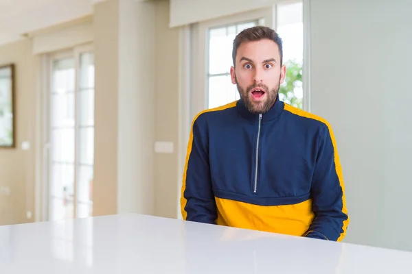 Handsome man at home afraid and shocked with surprise expression, fear and excited face.