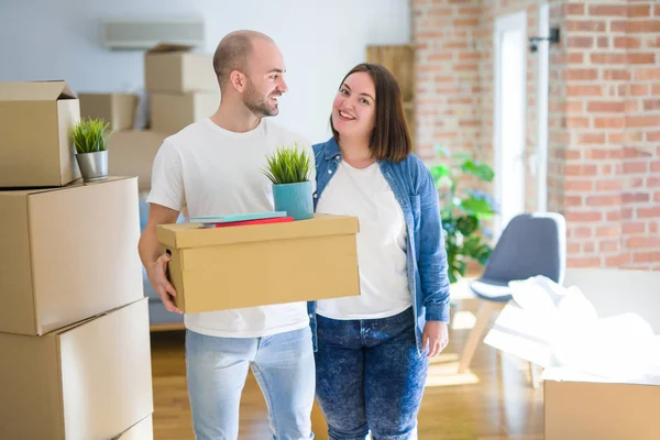 Pareja joven mudándose a un nuevo hogar, sonriendo feliz sosteniendo cardboa — Foto de Stock